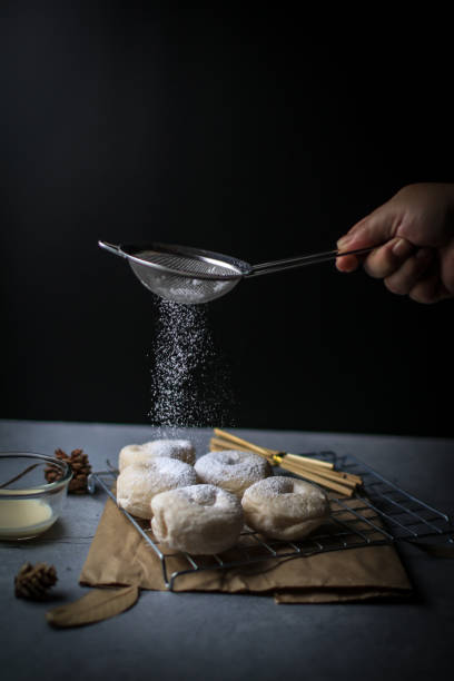 istock Fresh homemade donuts with powder sugar on the black dark rustic background. Falling powder sugar on donuts Breakfast concept, Selective focus. 1281176384