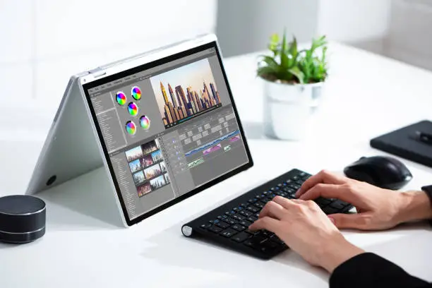 Photo of Cropped image of businesswoman using laptop at desk