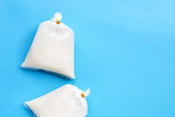 Soymilk in plastic bags on blue background. Top view