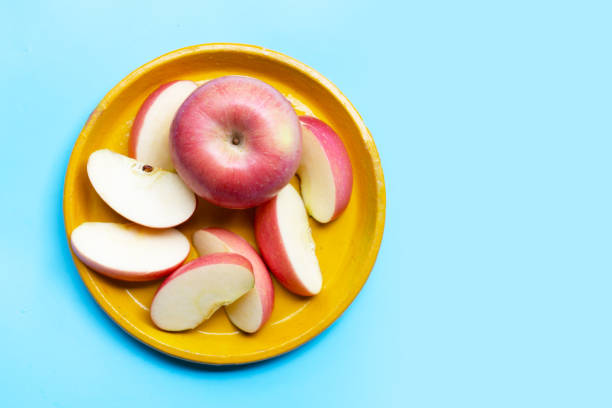 istock Fresh and juicy apples on yellow plat on blue background. 1281179365