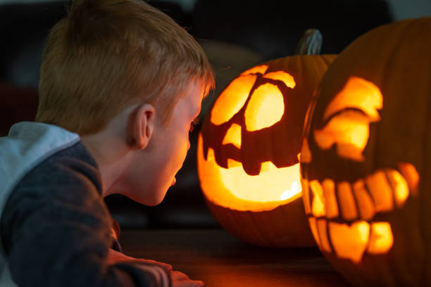 istock Young Cute Redhead Child Looking at Illuminated Pumpkin on Halloween 1281180179