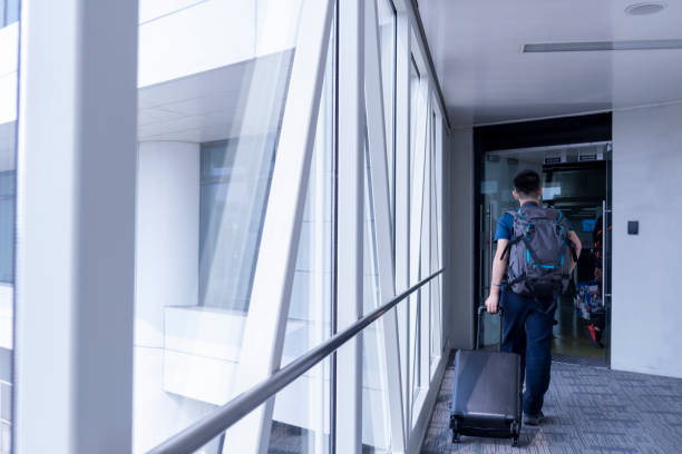 istock An Asian man pulling his suitcase in the passenger boarding bridge leading to the plane in the airport 1281181918