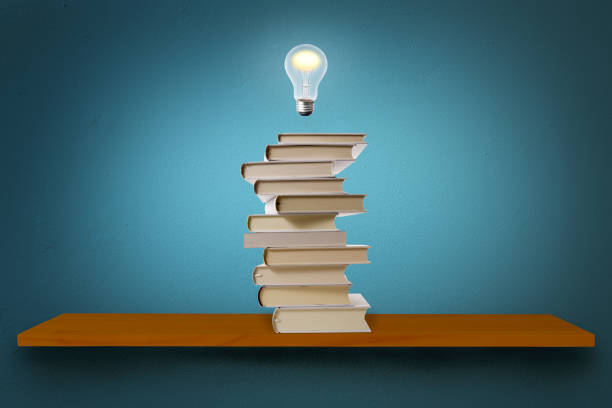 Glowing light bulb in mid-air over the blank books on a shelf against blue wall with copy space.