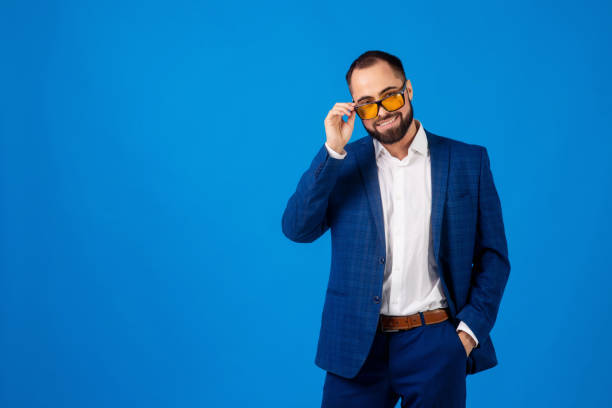 istock Young man wearing sunglasses in a classic blue suit on a blue background 1281184229