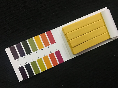 Litmus paper for pH testing. Litmus paper strips and color-coded pH ranges for comparative evaluation.