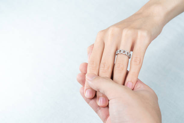 istock Man putting diamond ring on woman hand over white background. 1281192552
