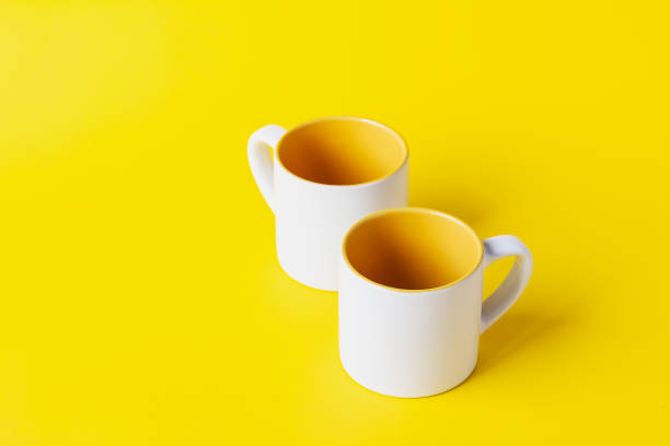 istock Empty coffee or tea white cup with yellow on yellow background. Copy space for text. 1281195663