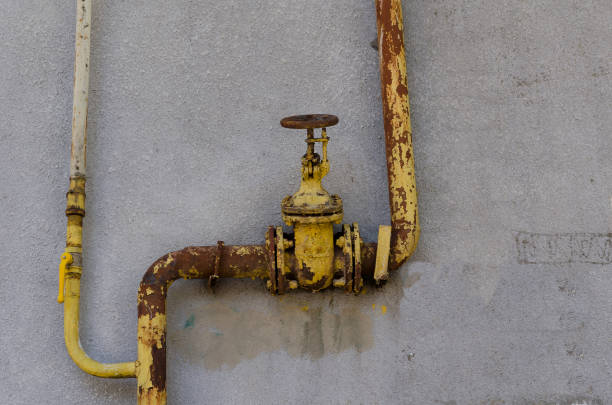 istock Old rusty yellow plumbing valve on a plastered wall. 1281203612