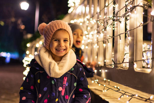 Children celebrating New Year A boy and a girl are outside near Christmas lights celebrating. new year urban scene horizontal people stock pictures, royalty-free photos & images