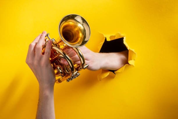 istock Hands playing pocket trumpet through torn yellow paper background 1281209805