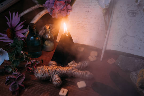 istock Open old book with magic spells, runes, black candle 1281210057