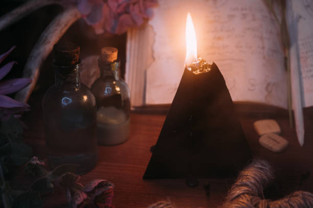 istock Open old book with magic spells, runes, black candle 1281210068