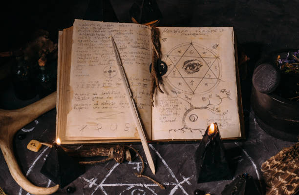 istock Open old book with magic spells, runes, black candles on witch table. Occult, esoteric, divination and wicca concept. 1281210153