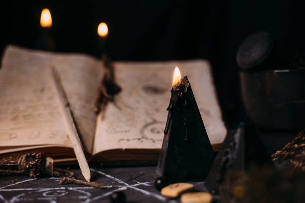 istock Open old book with magic spells, runes, black candles on witch table. Occult, esoteric, divination and wicca concept. 1281210155