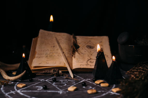 istock Open old book with magic spells, runes, black candles on witch table. Occult, esoteric, divination and wicca concept. 1281210158