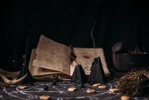 istock Open old book with magic spells, runes, black candles on witch table. Occult, esoteric, divination and wicca concept. 1281210168