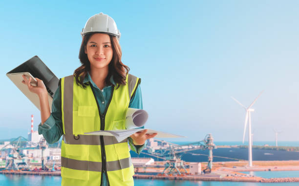 istock Female Civil engineer with computer and blueprint is standing infront on wind turbine for Sustainable energy industry development concept. 1281211449