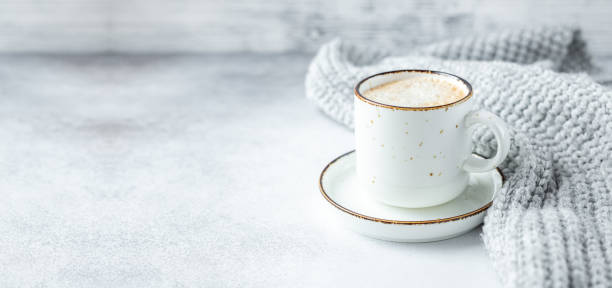 White mug with coffee and wool scarf on stone background. Winter composition in scandinavian style. Copy space for text stock photo