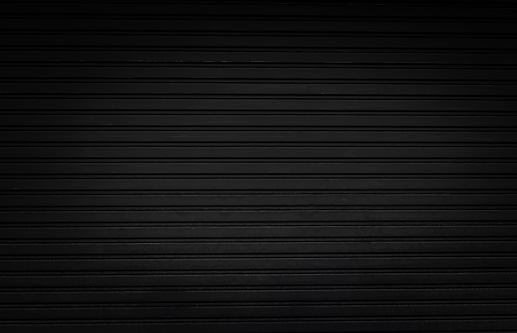 grunge black steel shutter door background and texture with vignette effect.