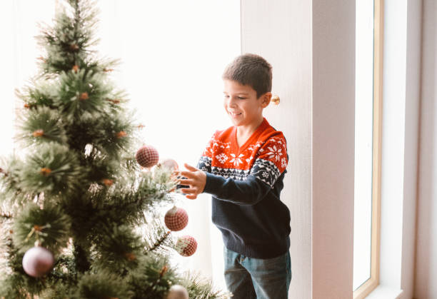 istock Little boy decorating Christmas tree at home. 1281215548