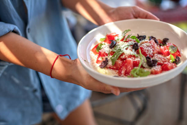 mujer joven sosteniendo queso parmesano, tomate y ensalada de menta fresca - mediteranean cuisine fotografías e imágenes de stock