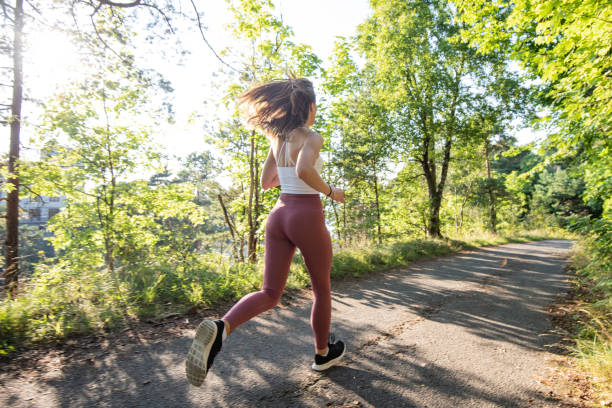 vue arrière de jeune femme sportive faisant courir à travers la forêt. - nordic running photos et images de collection