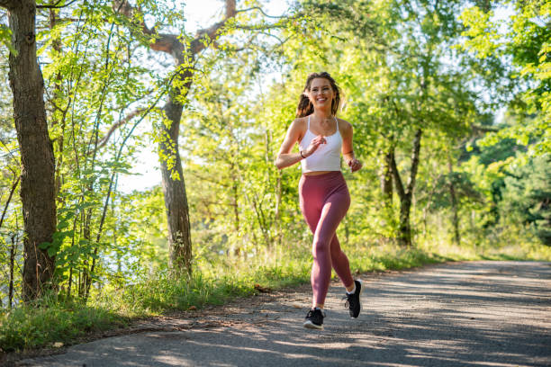 joven mujer deportiva corriendo por el bosque. - corredora de footing fotografías e imágenes de stock