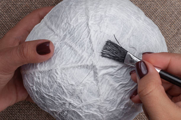 the process of creating a pumpkin from papier-mache, applying glue to the base , a hobby for Halloween decorations.