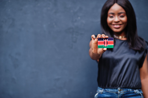 African woman hold small Kenya flag in hands.