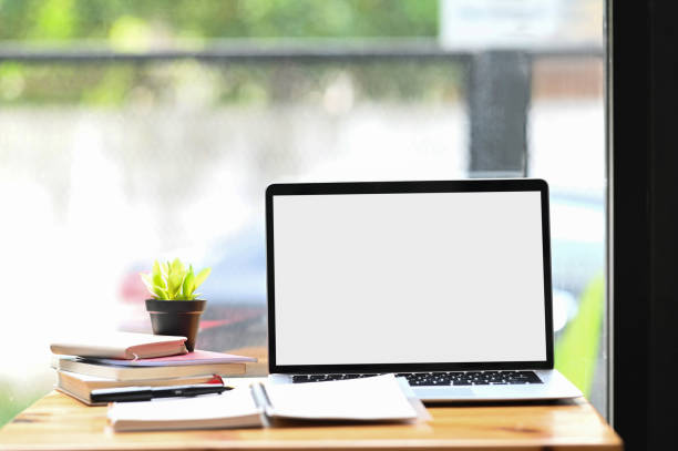 istock Workspace with blank screen desktop laptop, plant and notebooks on wooden desk. 1281227507