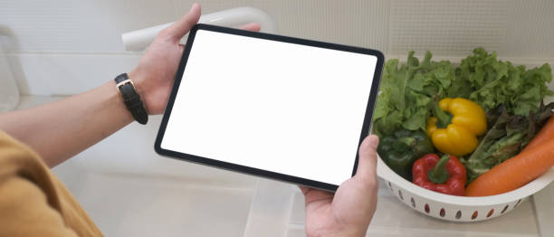 istock Cropped shot of man hands holding tablet with empty screen in the kitchen. 1281227682