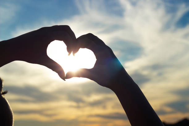 istock fingers folded in a heart on a sunset background 1281228324
