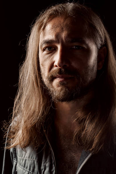 istock Long-haired masculine middle-aged man standing in the dark 1281232362
