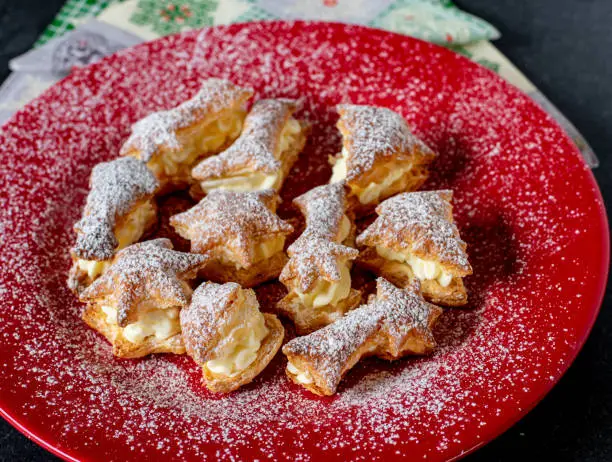 delicious christmas cream puffs in different shapes served on a red plate from above - ready to eat