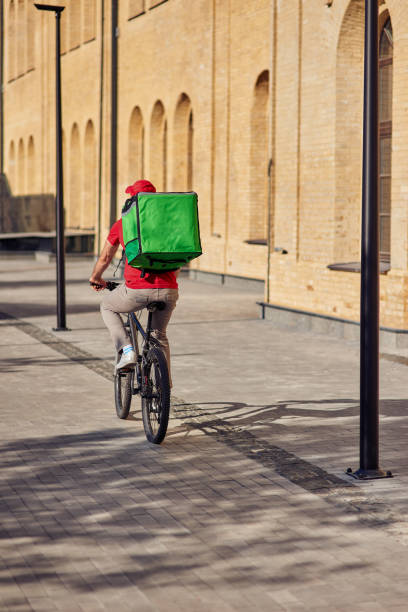 livreur avec le sac de réfrigérateur chevauchant le vélo - refrigeration cycle photos et images de collection