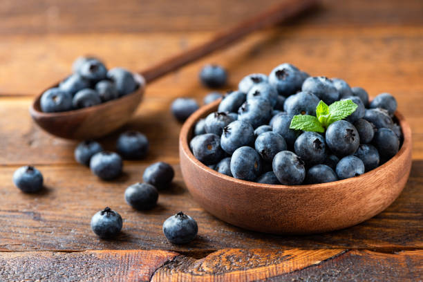 Blueberries in wooden bowl on a rustic wooden table stock photo