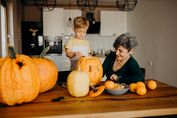istock Grandma helps her grandson cut pumpkin 1281233631