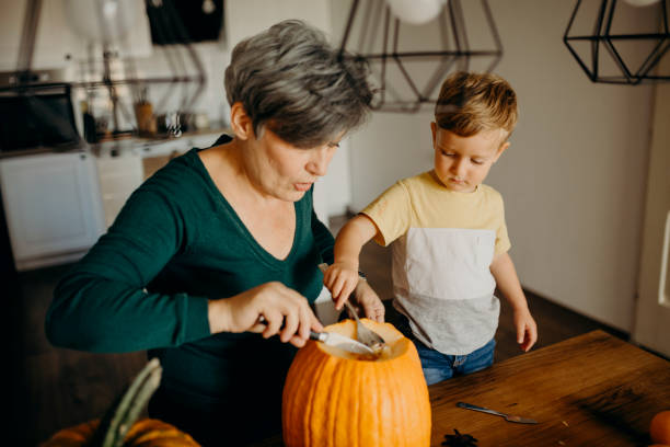istock Grandma helps her grandson cut pumpkin 1281233739