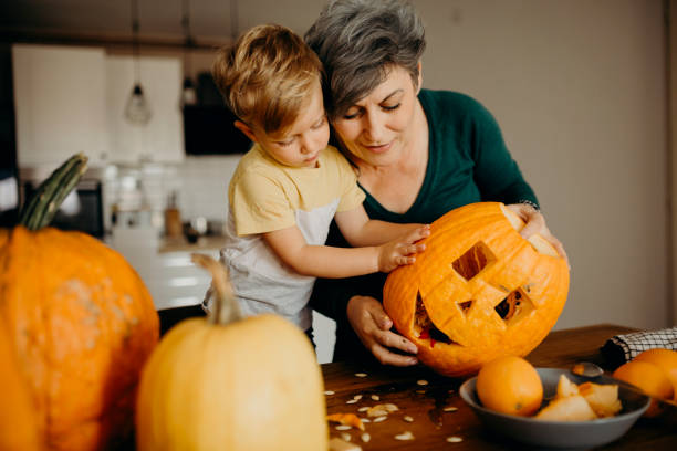 istock Grandma helps her grandson cut pumpkin 1281234178