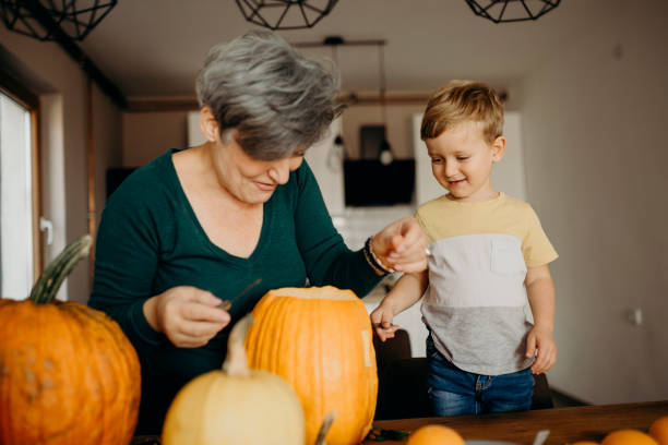 istock Grandma helps her grandson cut pumpkin 1281235237