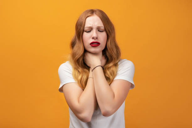 istock Frustrated girl with wavy redhead, keeps hands on neck, has painful strangle, asthmatic attack, hard to breath 1281235570