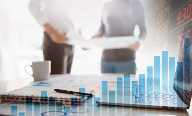 istock Two business people working together on corporate strategy. Try to analyze statistics. Financial forecast graph hologram. Double exposure. 1281235601