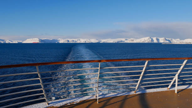 panorama view from the stern of a cruise ship with the vessel's wake in the arctic ocean and snow-covered mountains on the horizon near hammerfest, norway in winter time. - hammerfest imagens e fotografias de stock