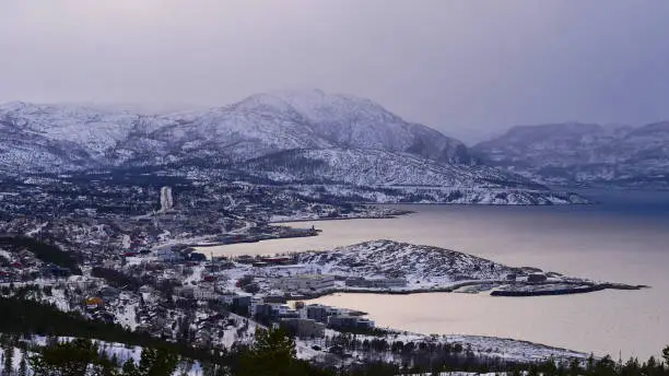 Panorama view over snow-covered city of Alta, Troms og Finnmark, Norway from the peak of Komsa with Altafjord and mountains on cloudy day in winter.