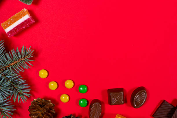 istock Chocolate and candy on a red background with a spruce sprig for Christmas. A banner with a place for text for a pastry shop. 1281238460