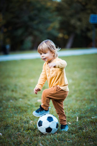 istock Little boy playing football alone on the grass. 1281243602
