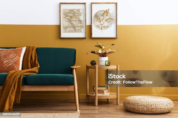 Stylish Scandinavian Interior Of Living Room With Design Green Velvet Sofa Gold Pouf Wooden Furniture Plants Carpet Cube And Mock Up Poster Frames Template Stock Photo - Download Image Now