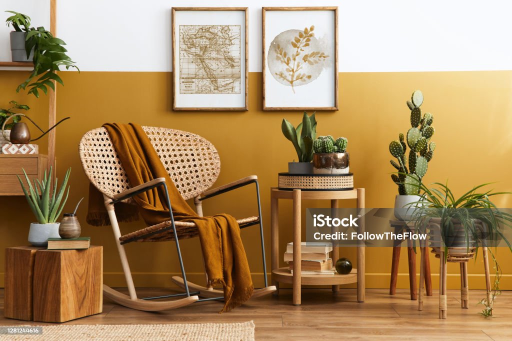 Stylish composition of living room interior with design rattan armchair, two mock up poster frames, plants, cube, palid and personal accessories in honey yellow home decor. Template. Stylish scandinavian interior of living room with design velvet sofa, furniture, plant and mock up poster frames. Template. Rattan Stock Photo