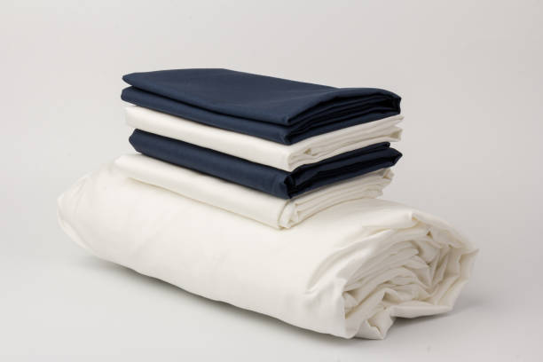 istock Stack of clean white and blue bed sheets on white  background, closeup. 1281245211