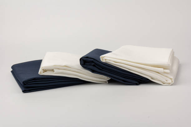 istock Stack of clean white and blue bed sheets on white  background, closeup. 1281245212